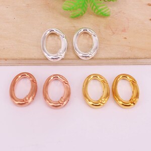 May include: An assortment of oval-shaped clasps in silver, rose gold, and gold. The clasps are open, showcasing their design and functionality. The clasps are likely used for jewelry making or crafting projects.