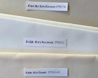 May include: Three different colors of Aida fabric swatches, labeled "AIDA 18CT AIDA PLATINUM 3793/770", "AIDA 18 CT ANT. WHITE 3793/101", and "AIDA 18 CT IVORY 3793/264".