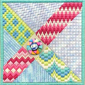 May include: A colorful patchwork quilt square with a multi-colored button in the center. The square is made up of four different fabrics, each with a different pattern. The button is a focal point of the design.