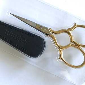 May include: Gold-colored embroidery scissors with a black leather case. The case has the word "Wrights" embossed on it.