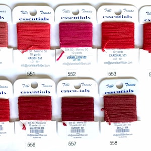 May include: A collection of ten skeins of red, pink, and maroon embroidery floss, each labeled with a color name and number. The floss is arranged in a grid pattern on a white background.