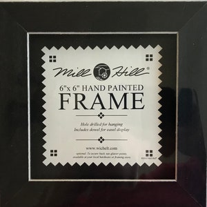 May include: Black wood picture frame with a white mat and a white label that reads "Mill Hill 6"x 6" HAND PAINTED FRAME". The label also includes the text "Hole drilled for hanging Includes dowel for easel display www.wichelt.com optional. To secure back, use glazier points, available at your local hardware or framing store. ©2010 Mill Hill"