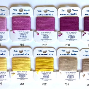 May include: Ten skeins of embroidery floss in various colors, including pink, purple, yellow, and beige. Each skein is labeled with the brand "Tilli Tomas essentials", the color name, and the lot number. The skeins are arranged in two rows of five.