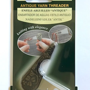 May include: Antique yarn threader with a clover design. The threader is made of metal and has a silver finish. The packaging is green and has the text "Clover" and "Antique Yarn Threader" on it. The text "ENFILE-AIGUILLES "ANTIQUE"" is also on the packaging.