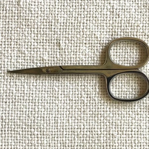 May include: A pair of small, silver-colored cuticle scissors with a pointed tip.