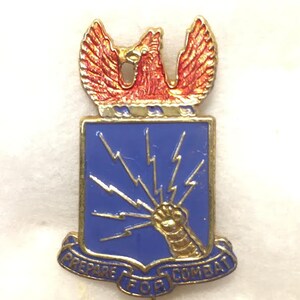 May include: A gold-colored military pin with a blue shield, a red eagle, and the words "Prepare for Combat".