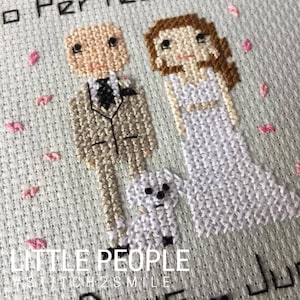 Op de afbeelding: Borduurwerk met kruissteek van een bruidspaar met een kleine witte hond. De bruidegom draagt een beige pak met een zwarte stropdas. De bruid draagt een witte jurk. De tekst "LITTLE PEOPLE #STITCH2SMILE" staat onderaan de afbeelding.