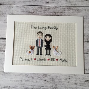 Puede incluir: Un bordado de punto de cruz enmarcado en blanco con el texto "The Lung Family" en la parte superior. Debajo del texto hay dos figuras de palo, un hombre y una mujer, y dos perros. El texto "Peanut ♥ Jack ♥ Ali ♥ Molly" está en la parte inferior.