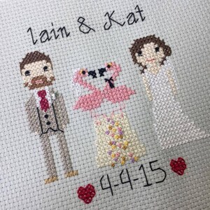 Puede incluir: Bordado de punto de cruz con una pareja, Lain & Kat, con dos flamencos rosas y un corazón con la fecha 4-4-15. La pareja está vestida con atuendo de boda.