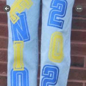 large, stylized lettering in blue glitter and yellow glitter htv. The letters appear to spell out senior class of 2026 which can be changed to any date Example 2027