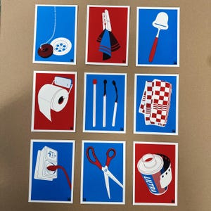 May include: Nine illustrated cards with a red and blue background. Each card features a different household item, such as a toilet paper roll, a drain stopper, a film canister, a pair of scissors, a dish towel, a set of matches, a cheese grater, a tea towel, and a set of clothespins.