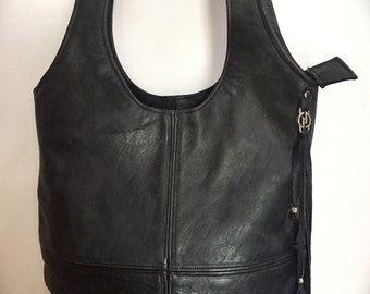May include: A black leather tote bag with a unique, oval-shaped top opening. The bag has a flap closure and a tassel detail.