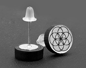 Round studs symbol seed of life or flower of life. Engraving and laser cutting on black acrylic and metallic. Creation of fertility