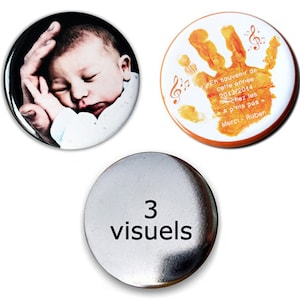 Peut inclure: Trois boutons ronds, un avec un bébé dormant dans une main, un avec une empreinte de main orange et des notes de musique, et un bouton argenté avec le texte "3 visuels".