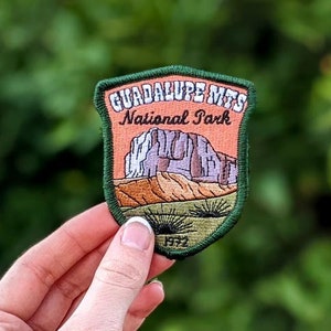 May include: A green embroidered patch with the text "Guadalupe Mts. National Park" and a depiction of a mountain range. The patch has a white border and the year "1972" in the bottom center.