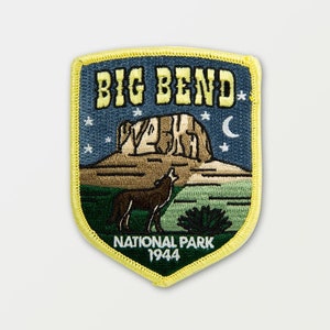 Könnte beinhalten: Ein blauer und gelber gestickter Aufnäher mit dem Text "BIG BEND NATIONAL PARK 1944". Der Aufnäher zeigt eine Bergkette, einen Coyote, der zum Mond heult, und Sterne am Nachthimmel.