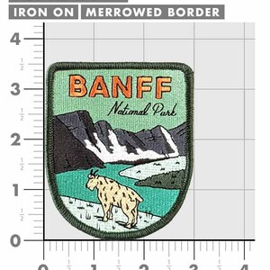 May include: A rectangular iron-on patch with a merrowed border, measuring 3.5" x 3". The patch features the text "BANFF National Park" above a mountain and lake scene with a goat. The patch has a green, black, and tan color scheme.