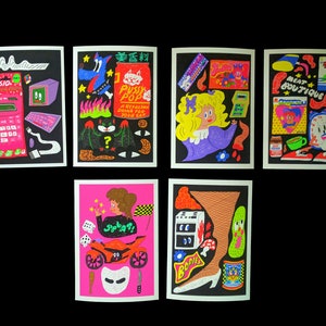 May include: Six colorful illustrated cards with black borders. Each card features a different design with a variety of objects and characters. The designs include a calculator, a cat drink, a girl with blonde hair, a clock, a motorcycle, and a leg with a shoe.