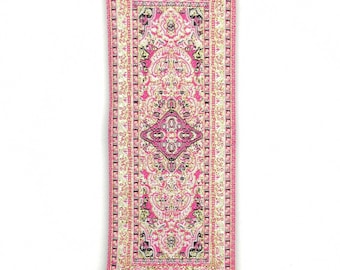 May include: A pink and gold patterned fabric rug hanging from a silver metal frame with a blue evil eye charm hanging below.