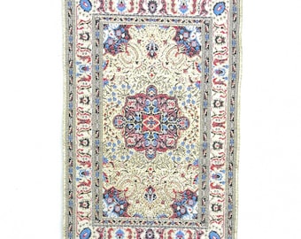 May include: A silver wall hanging with a blue evil eye charm. The wall hanging features a patterned fabric design that resembles a rug.