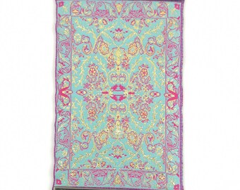 May include: A turquoise and pink patterned fabric wall hanging with a silver metal frame and a blue evil eye charm hanging from it.
