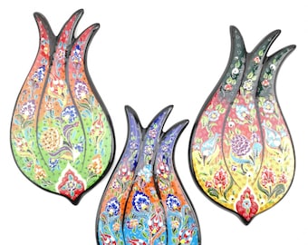 May include: Three ceramic tulip-shaped wall decor pieces with intricate floral patterns in shades of green, blue, and yellow. The tulips have black outlines and are painted with vibrant colors.