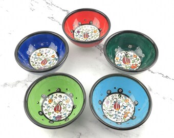 May include: Set of five small ceramic bowls with floral designs. The bowls are in various colors, including red, blue, green, and light blue. Each bowl has a black rim and a white background with a colorful floral pattern.