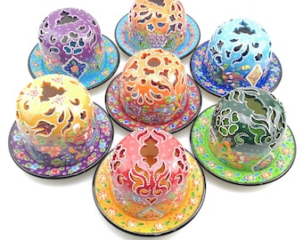 May include: Set of six colorful ceramic candle holders with intricate floral designs and cut-out patterns. Each holder has a matching plate.