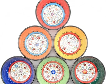 May include: A collection of six ceramic bowls in a variety of colors, including red, orange, yellow, green, blue, and dark green. Each bowl features a floral design in the center and a contrasting border. The bowls are arranged in a triangular shape.