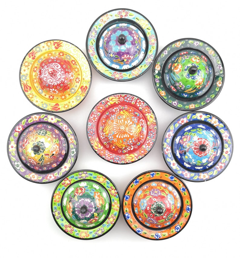 May include: Eight colourful ceramic bowls with lids, each featuring a different floral design. The bowls are arranged in a circle on a white background.