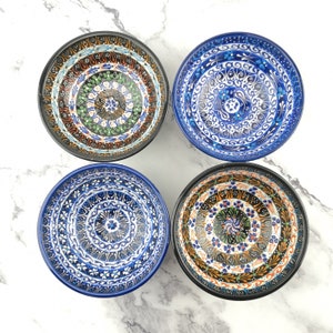 May include: Four ceramic bowls with intricate blue, green and orange patterns. The bowls have a black rim and are ideal for serving snacks or desserts.