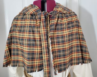 May include: A hooded plaid cape with a frayed edge and a tie at the neck. The cape is made of a brown, yellow, and red plaid fabric.