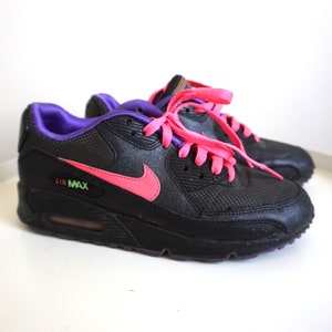 May include: Black Nike Air Max sneakers with pink laces and a purple trim. The Nike swoosh is pink.