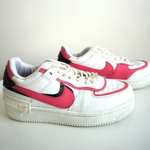 Puede incluir: Zapatillas blancas y rosas con detalles en negro. Las zapatillas presentan un logotipo y ribete rosa, con la marca "AIR" en la entresuela. Los cordones son blancos y el dise&ntilde;o es deportivo y moderno.