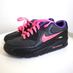 May include: Black sneakers with pink laces and a pink Nike swoosh. The sneakers have a purple trim and the text "AIR MAX" on the side.