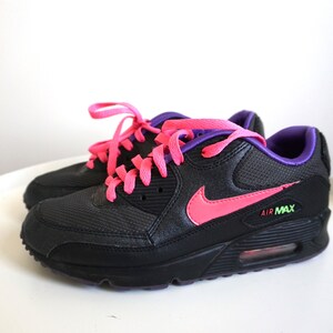 May include: Black Nike Air Max sneakers with pink and purple laces. The Nike swoosh is pink.
