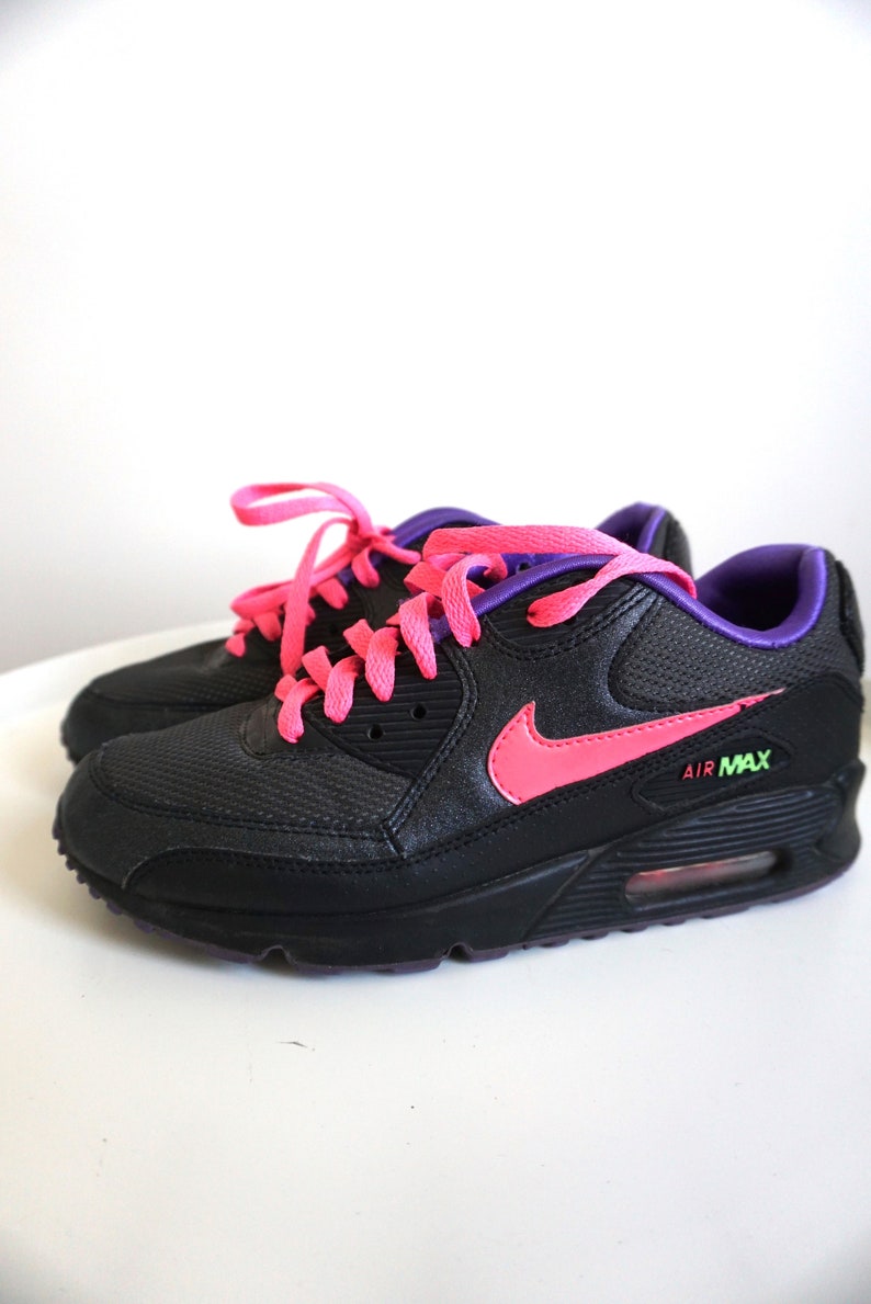 May include: Black Nike Air Max sneakers with pink and purple laces. The Nike swoosh is pink.