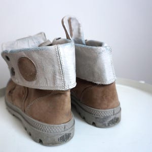 K&ouml;nnte beinhalten: Eine wei&szlig;e Keramik-Tasse mit schwarzem Henkel und dem Text "But First, Coffee" in fetter, schwarzer Schrift. Die Tasse steht vor einem verschwommenen Hintergrund, der eine gem&uuml;tliche Umgebung suggeriert. Die Tasse ist etwa 10 cm hoch.