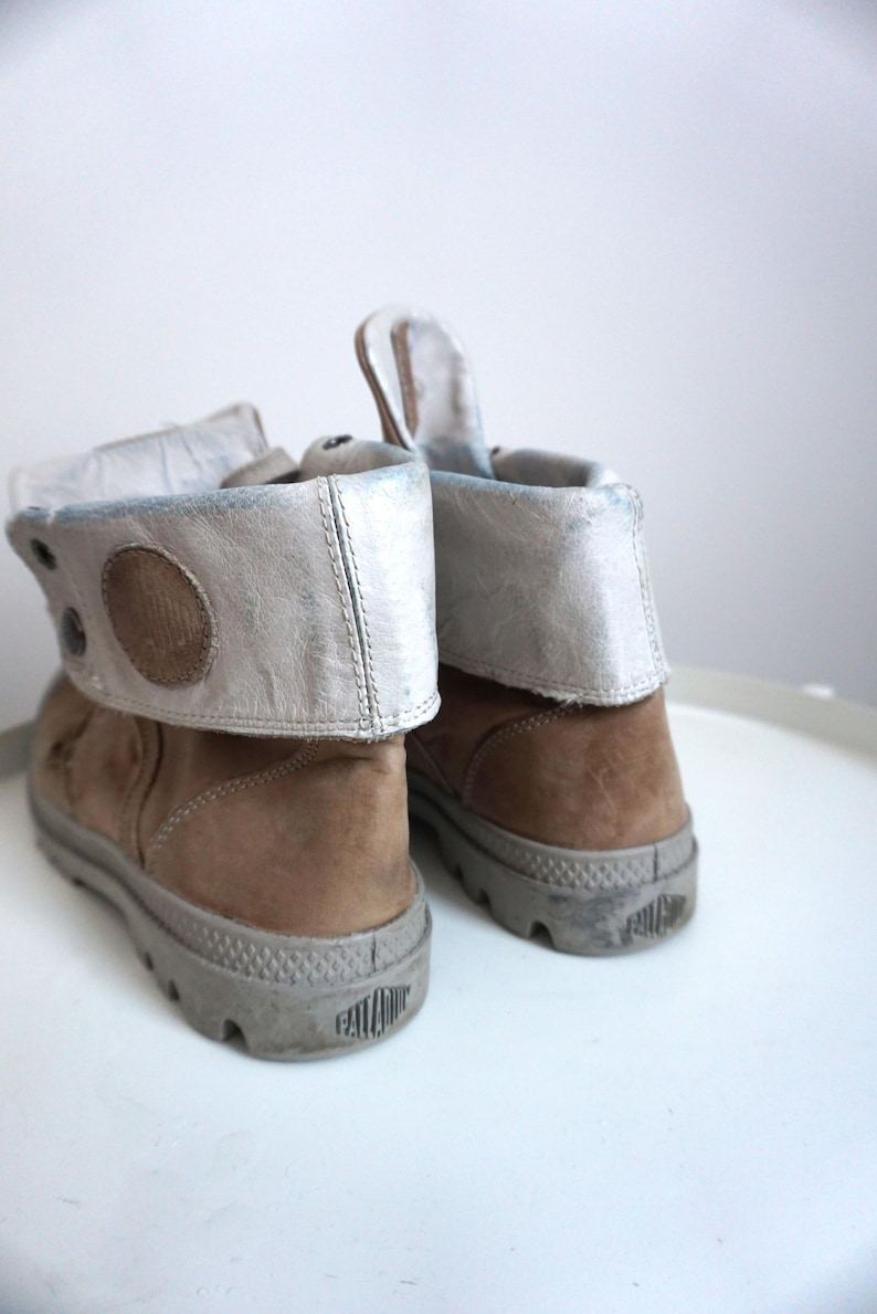 K&ouml;nnte beinhalten: Eine wei&szlig;e Keramik-Tasse mit schwarzem Henkel und dem Text "But First, Coffee" in fetter, schwarzer Schrift. Die Tasse steht vor einem verschwommenen Hintergrund, der eine gem&uuml;tliche Umgebung suggeriert. Die Tasse ist etwa 10 cm hoch.