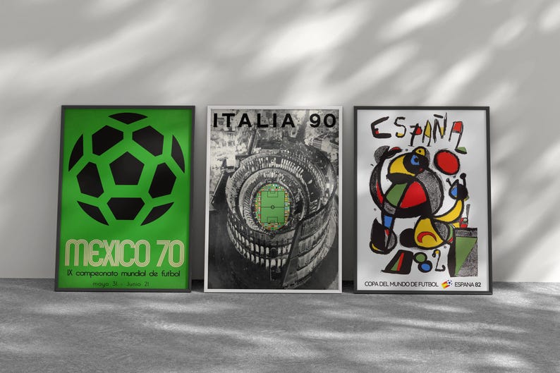 May include: Three framed posters featuring soccer tournament art. The left poster is green with a black soccer ball and text reading MEXICO 70. The center poster shows a stadium with ITALIA 90 text. The right poster features abstract art and ESPA&Ntilde;A 82 text.