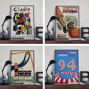 May include: A set of four framed posters featuring vintage soccer tournament artwork. The prints display historical World Cup graphics from 1930, 1950, 1982, and 1994, showcasing various artistic styles, bold colors, and tournament text.