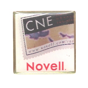 May include: A square pin with a clear, glossy finish. The pin features a design with the letters "CNE" in white, a blurred image, and the word "Novell" in red. The website address "www.sayell.com/inc" is also visible.
