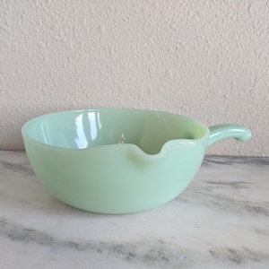 May include: A light green vintage Pyrex mixing bowl with a pouring spout and a handle.