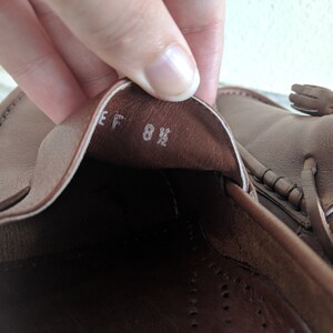 May include: Close-up of the inside of a brown leather loafer with a white label that reads "EF 8 1/2".