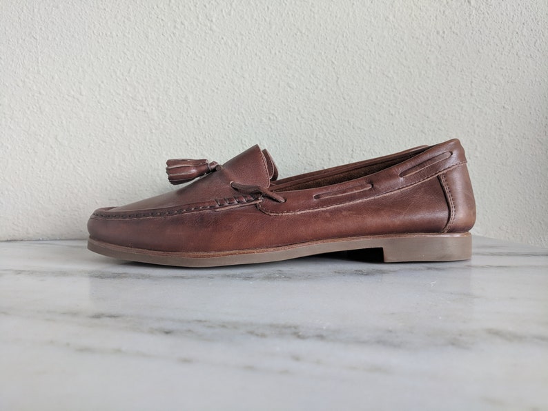 May include: Brown leather tassel loafers with a brown leather sole.