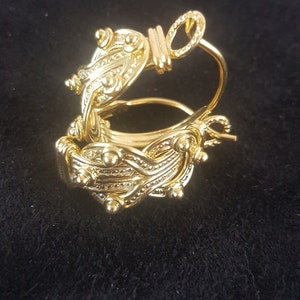 Op de afbeelding: Gouden creolen met een gedetailleerd, ingewikkeld ontwerp. De oorbellen zijn gemaakt van een geweven patroon met kleine kralen en een ronde accent.