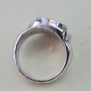 K&ouml;nnte beinhalten: Ein silberner Ring mit einem strukturierten, abgerundeten Design. Der Ring ist aus Metall und hat eine glatte, polierte Oberfl&auml;che.