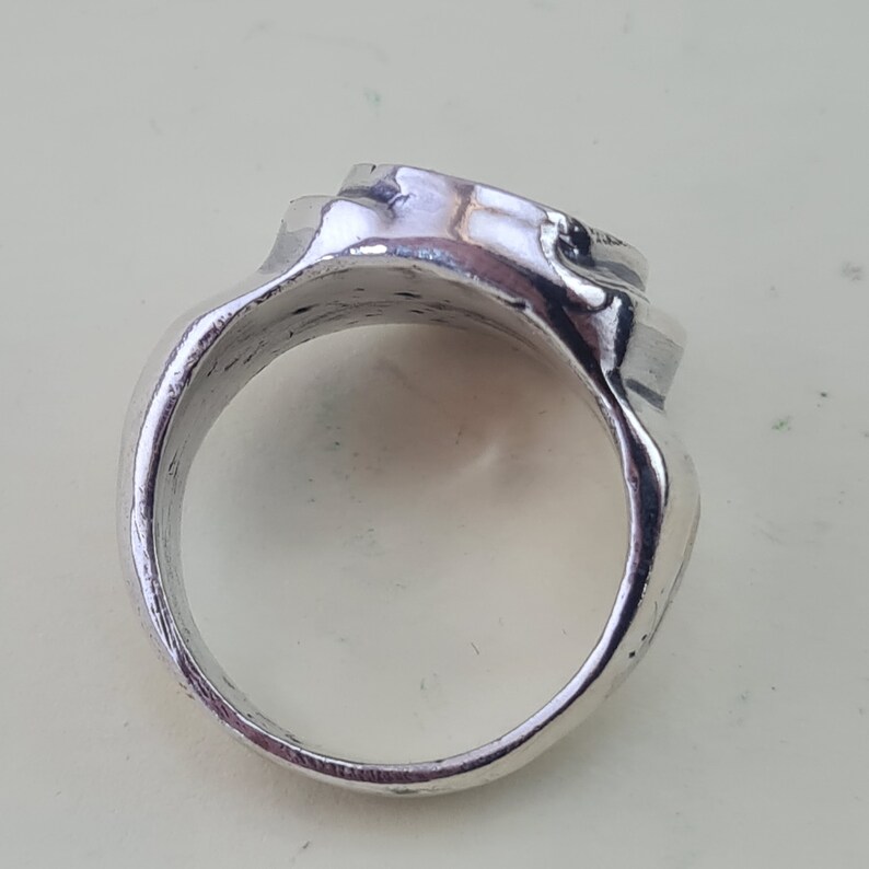 K&ouml;nnte beinhalten: Ein silberner Ring mit einem strukturierten, abgerundeten Design. Der Ring ist aus Metall und hat eine glatte, polierte Oberfl&auml;che.
