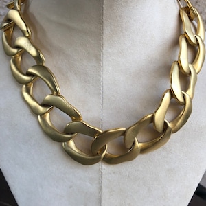 May include: A thick gold chain necklace with large, chunky links. The necklace is displayed on a white mannequin.
