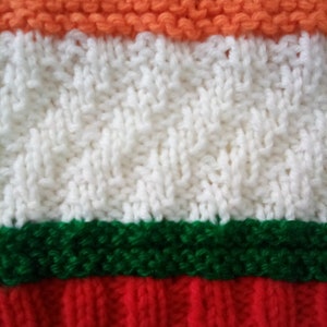 Peut inclure: Un tissu tricot&eacute; avec des rayures orange, blanches, vertes et rouges. Le tissu est r&eacute;alis&eacute; avec une vari&eacute;t&eacute; de points, cr&eacute;ant un aspect textur&eacute;.